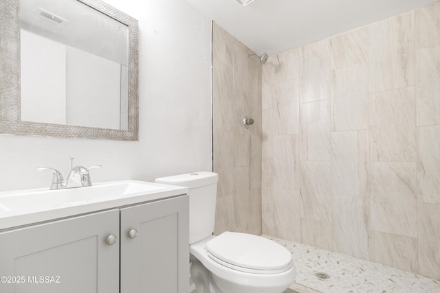 bathroom featuring tiled shower, vanity, and toilet