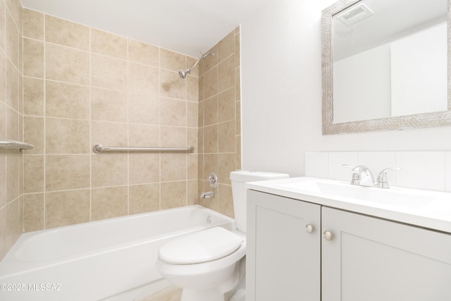 full bathroom featuring vanity, tiled shower / bath combo, and toilet