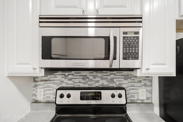 kitchen with stainless steel appliances, white cabinets, and backsplash