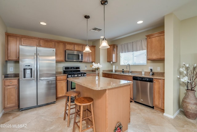 kitchen with visible vents, a kitchen island, stainless steel appliances, pendant lighting, and a sink