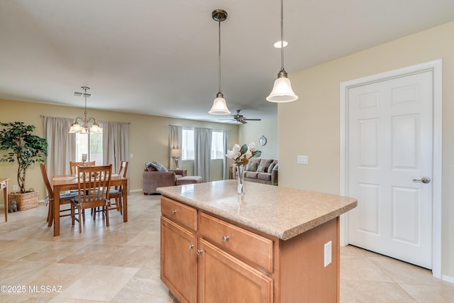 kitchen featuring visible vents, open floor plan, decorative light fixtures, a center island, and light countertops