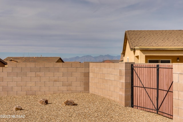 view of yard featuring a gate, fence, and a mountain view