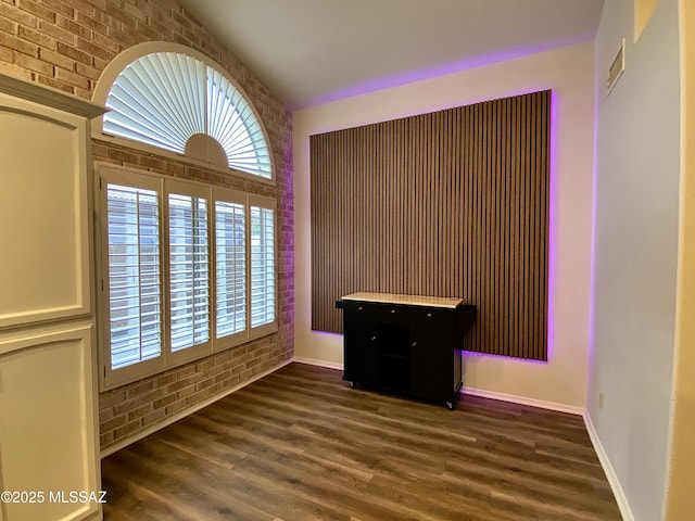 unfurnished room featuring dark hardwood / wood-style floors and brick wall