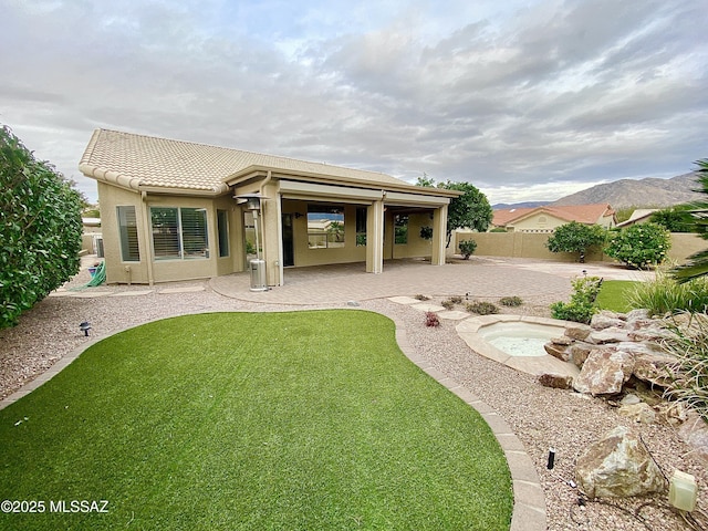 back of property featuring a mountain view, a patio, and a lawn