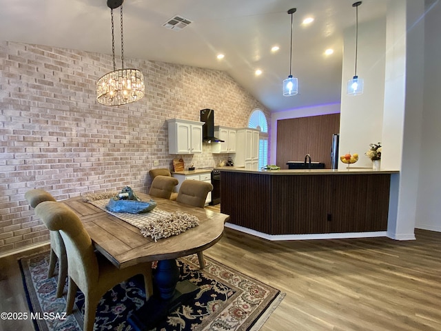 dining room with brick wall, lofted ceiling, and dark hardwood / wood-style flooring