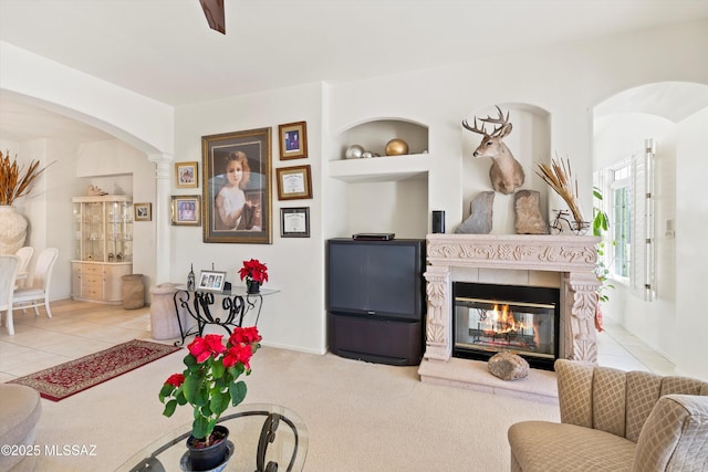 living room featuring light tile patterned floors, built in shelves, a multi sided fireplace, and light colored carpet