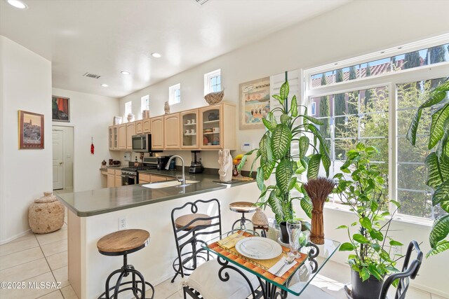 kitchen with dark countertops, visible vents, glass insert cabinets, appliances with stainless steel finishes, and a peninsula