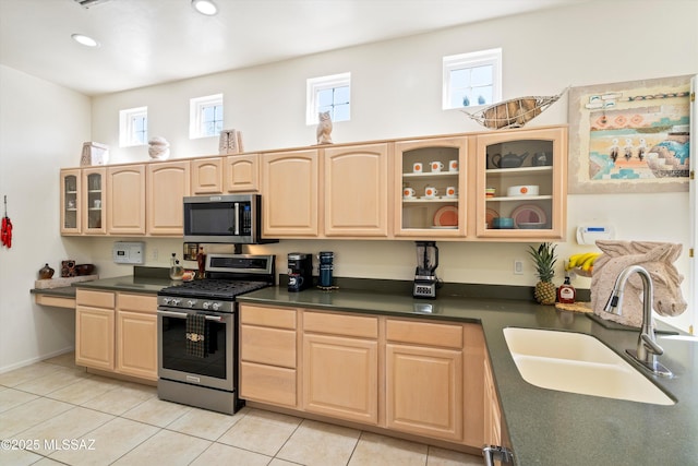 kitchen with stainless steel appliances, dark countertops, glass insert cabinets, and a sink