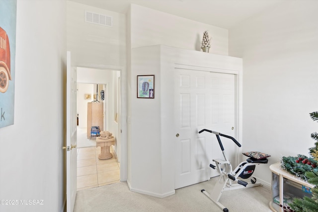 exercise room featuring visible vents, light carpet, and baseboards