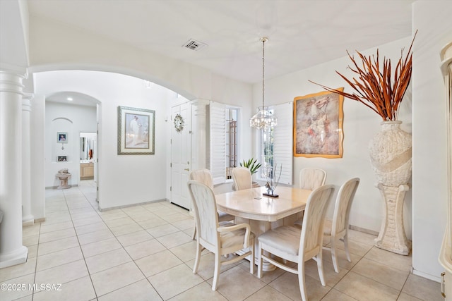 dining room with visible vents, arched walkways, ornate columns, a notable chandelier, and light tile patterned flooring