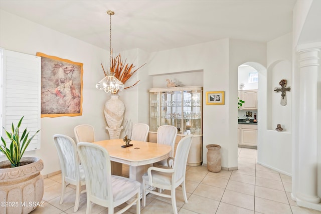 dining area with light tile patterned floors, baseboards, arched walkways, and an inviting chandelier