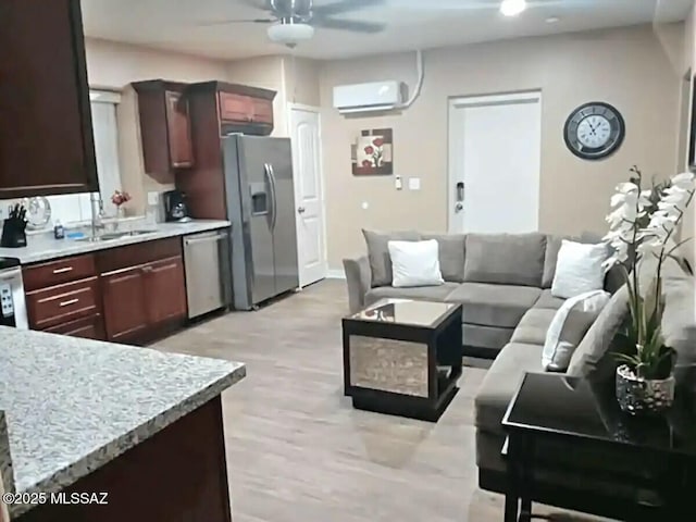 kitchen with sink, a wall mounted AC, appliances with stainless steel finishes, ceiling fan, and light hardwood / wood-style floors