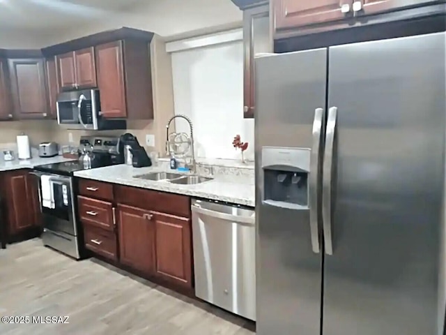 kitchen featuring appliances with stainless steel finishes, sink, and light hardwood / wood-style flooring