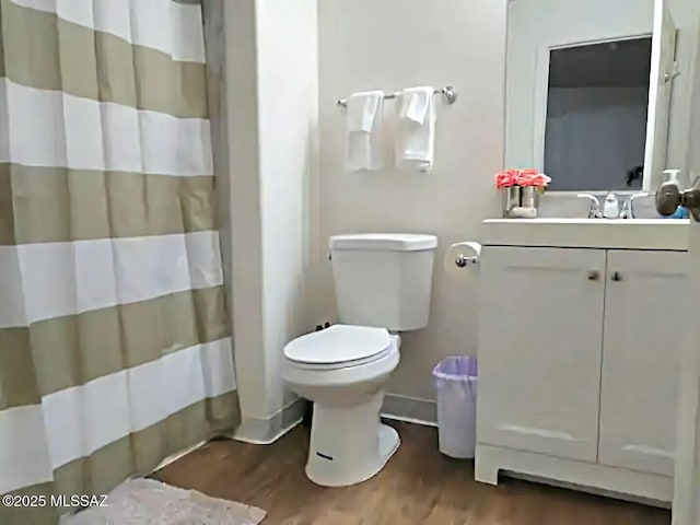 bathroom featuring wood-type flooring, curtained shower, vanity, and toilet