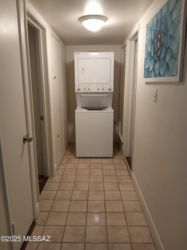 laundry area featuring stacked washer and dryer and light tile patterned floors