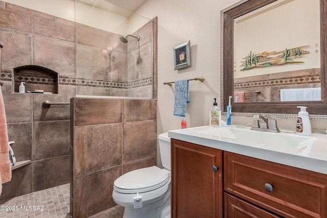 bathroom featuring vanity, tiled shower, and toilet