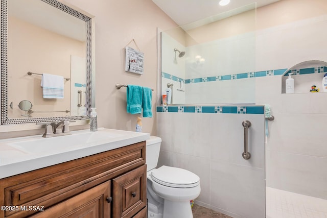 bathroom featuring toilet, vanity, and tiled shower