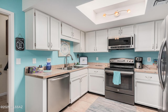 kitchen featuring a tray ceiling, sink, stainless steel appliances, and white cabinetry