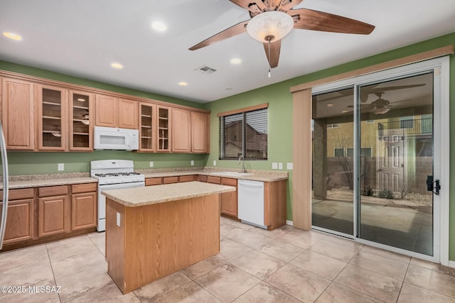 kitchen featuring ceiling fan, a kitchen island, sink, and white appliances