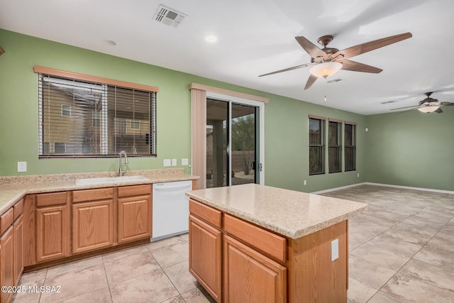 kitchen with sink, white dishwasher, a kitchen island, ceiling fan, and light stone countertops