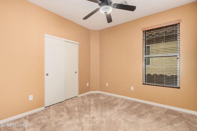 unfurnished bedroom featuring ceiling fan, light colored carpet, and a closet