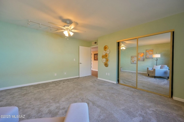 unfurnished bedroom with rail lighting, carpet floors, a closet, and ceiling fan