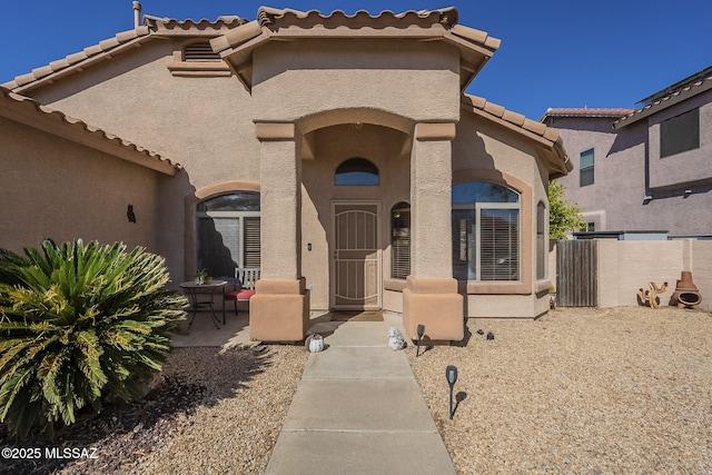 view of front of house with fence, a patio, and stucco siding