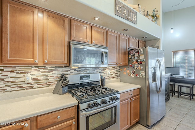 kitchen with stainless steel appliances, brown cabinetry, light countertops, and decorative light fixtures