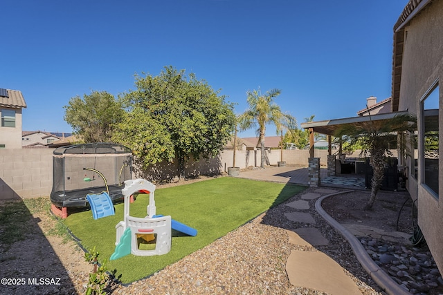 view of yard with a patio area, a fenced backyard, and a trampoline