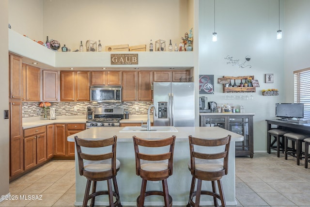 kitchen featuring a breakfast bar, a towering ceiling, light countertops, appliances with stainless steel finishes, and hanging light fixtures