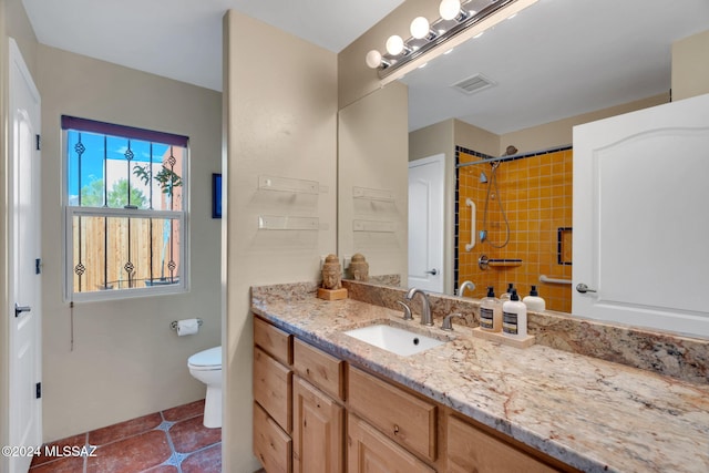 bathroom featuring vanity, toilet, tile patterned flooring, and a tile shower