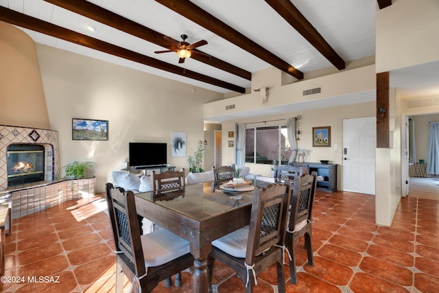 tiled dining room with beamed ceiling, ceiling fan, and a fireplace