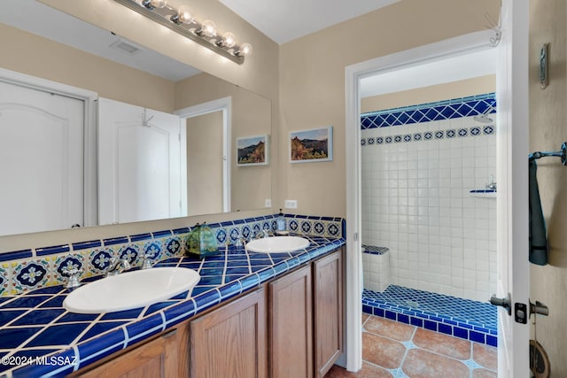 bathroom with tiled shower, vanity, and tile patterned floors