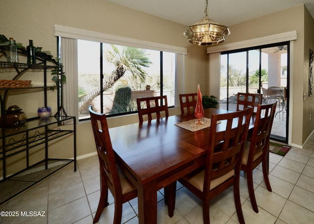 dining area with light tile patterned floors, baseboards, and an inviting chandelier