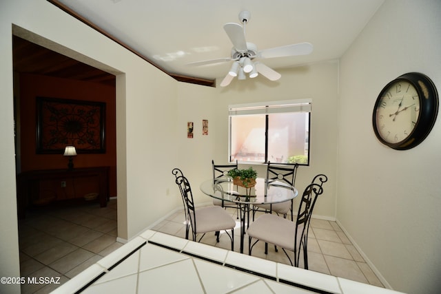 dining space with a ceiling fan, light tile patterned flooring, and baseboards