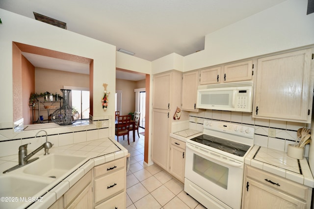 kitchen featuring tile counters, white appliances, visible vents, and a sink