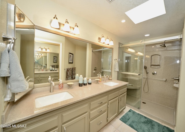 bathroom with a stall shower, tile patterned flooring, a sink, and a skylight