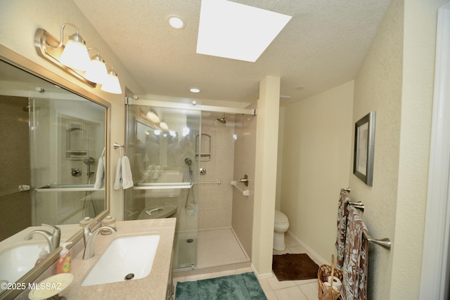 bathroom with a textured ceiling, tile patterned flooring, toilet, vanity, and a stall shower