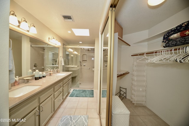 full bathroom with a skylight, a sink, visible vents, and tile patterned floors