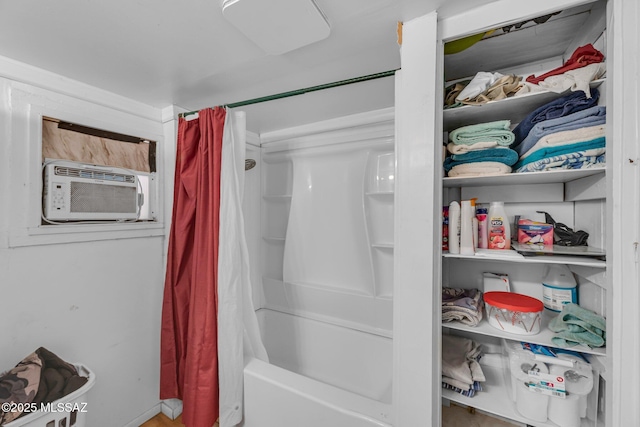 bathroom featuring cooling unit and shower / bath combination with curtain