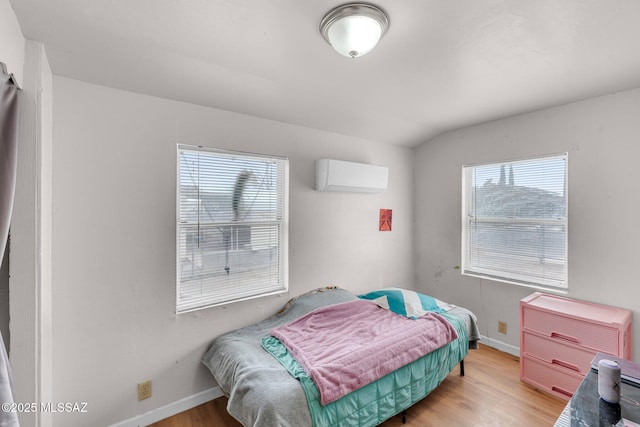 bedroom with lofted ceiling, light wood-type flooring, and an AC wall unit