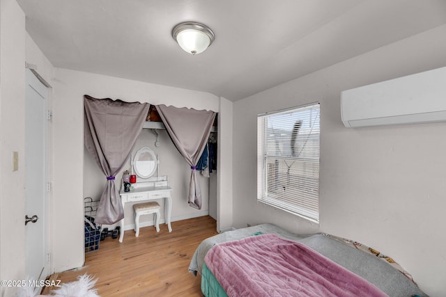 bedroom with a wall unit AC and light wood-type flooring
