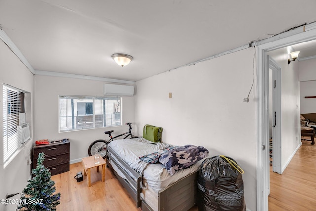 bedroom with a wall mounted AC and light hardwood / wood-style floors