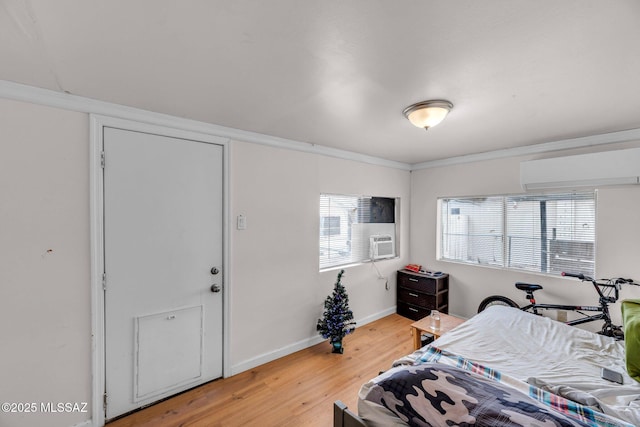bedroom featuring hardwood / wood-style flooring, ornamental molding, and a wall unit AC
