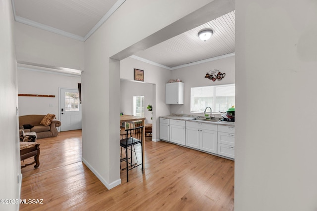 kitchen featuring white cabinetry, sink, crown molding, and light hardwood / wood-style flooring