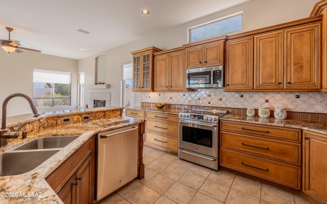 kitchen with sink, light stone countertops, stainless steel appliances, and decorative backsplash