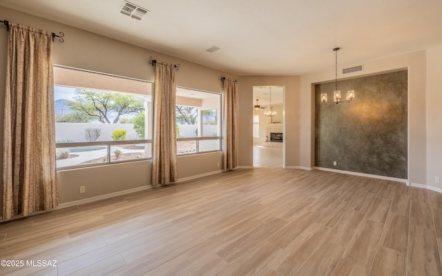 unfurnished room featuring a chandelier and light hardwood / wood-style floors