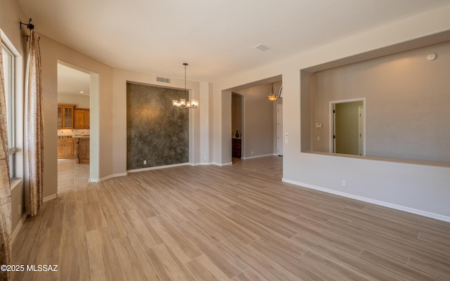 empty room featuring light wood-type flooring and a chandelier