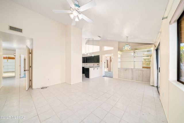 unfurnished living room with light tile patterned flooring, ceiling fan, and high vaulted ceiling