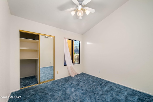 unfurnished bedroom featuring ceiling fan, vaulted ceiling, a closet, and dark colored carpet